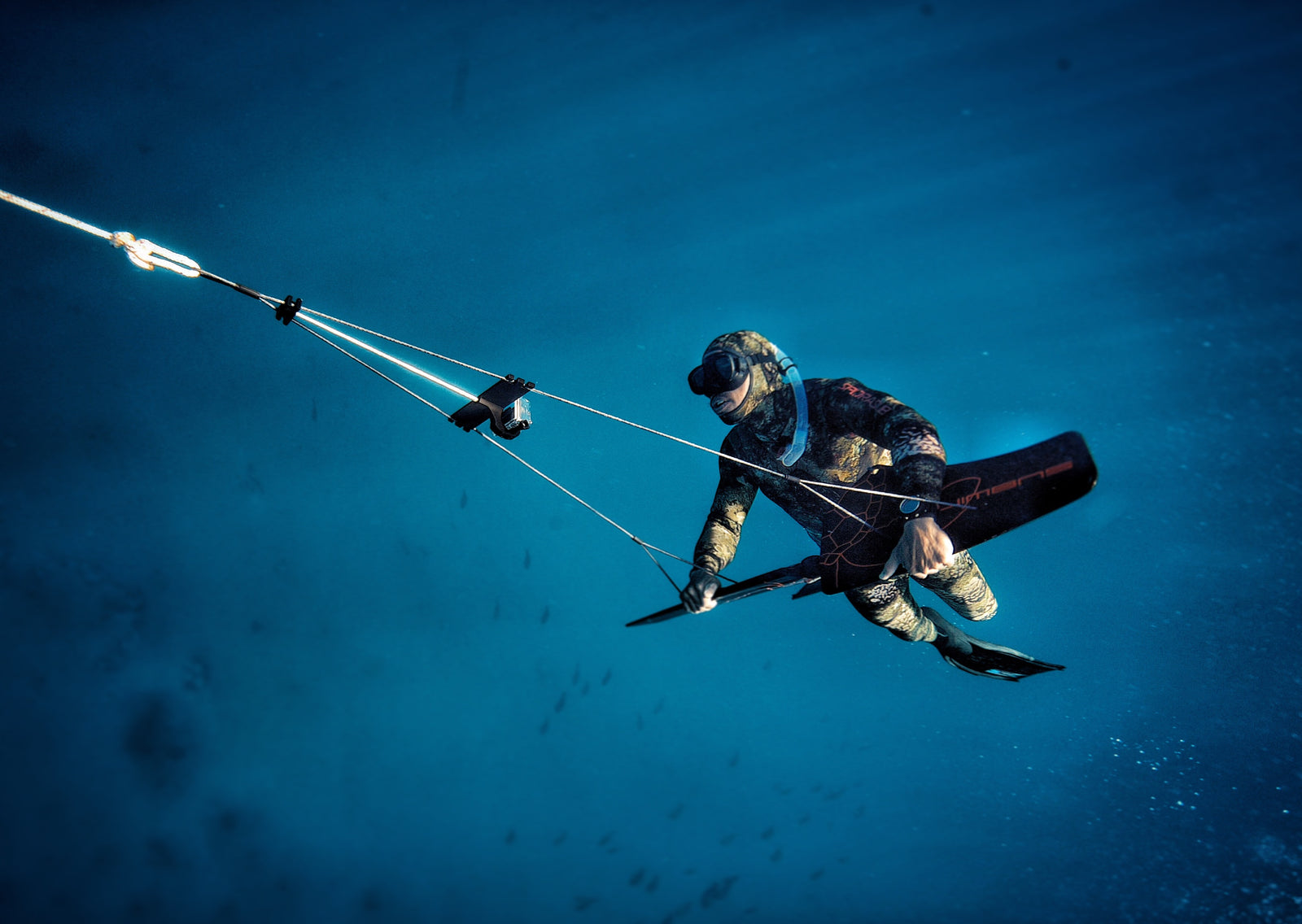 freediver with camo wetsuit subwinging with gopro mount