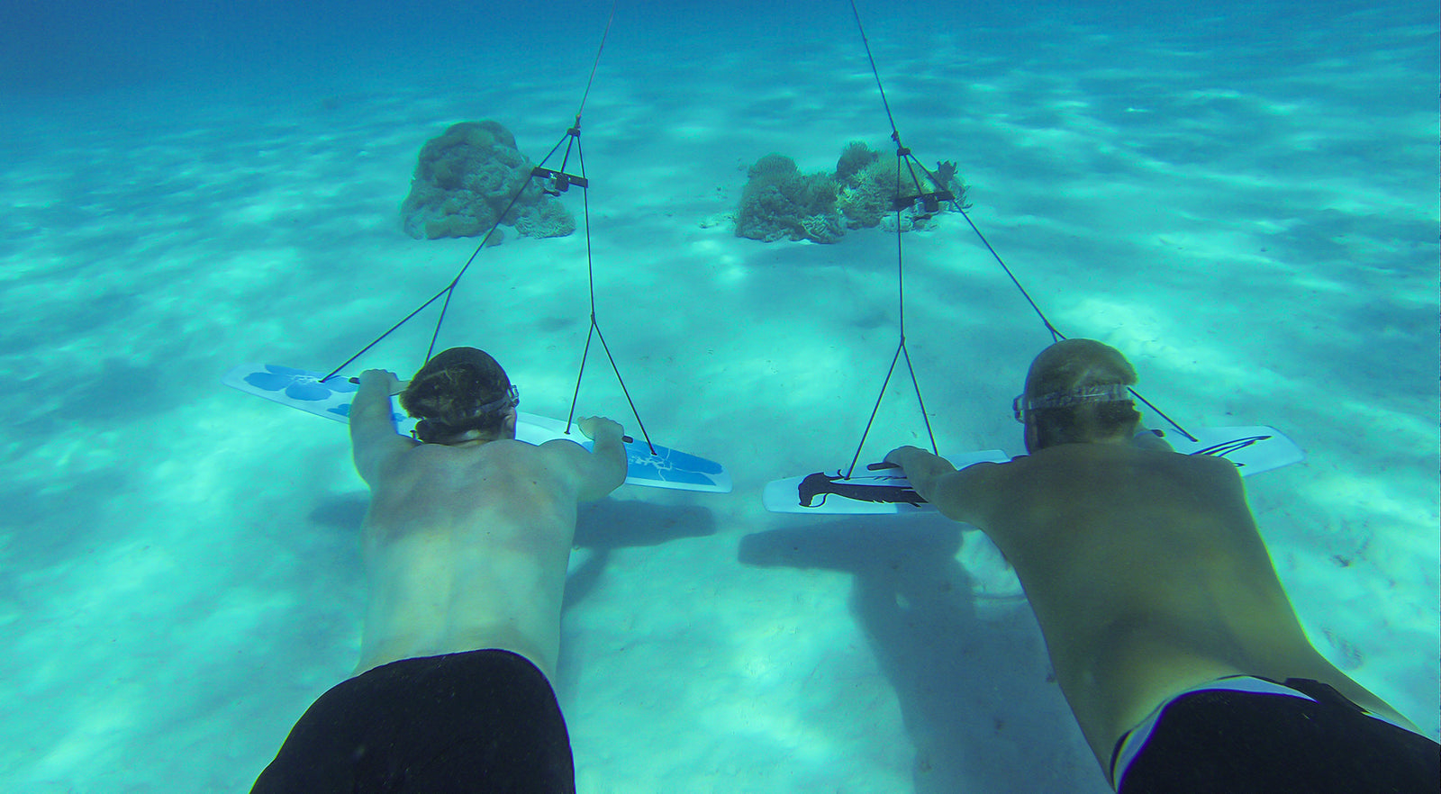 Two subwing riders close to sand bottom rear view