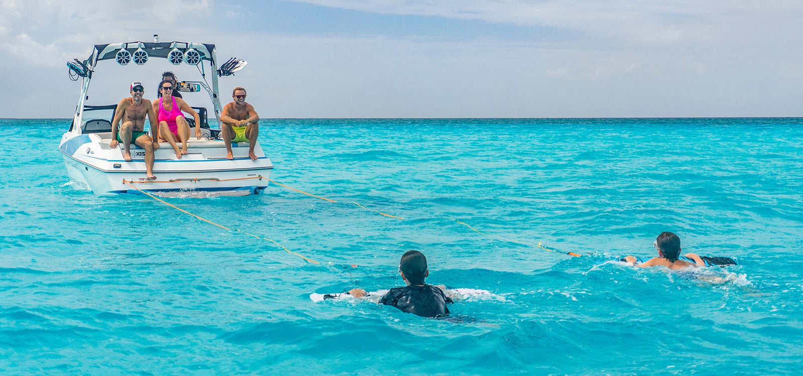 two kids towed on subwing with parents watching on boat