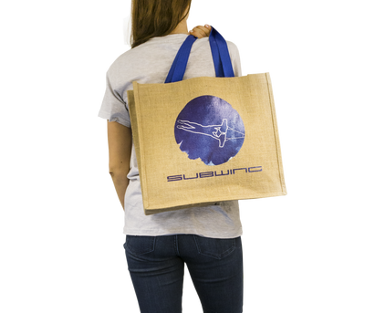 Woman holding jute beach bag with Subwing logo